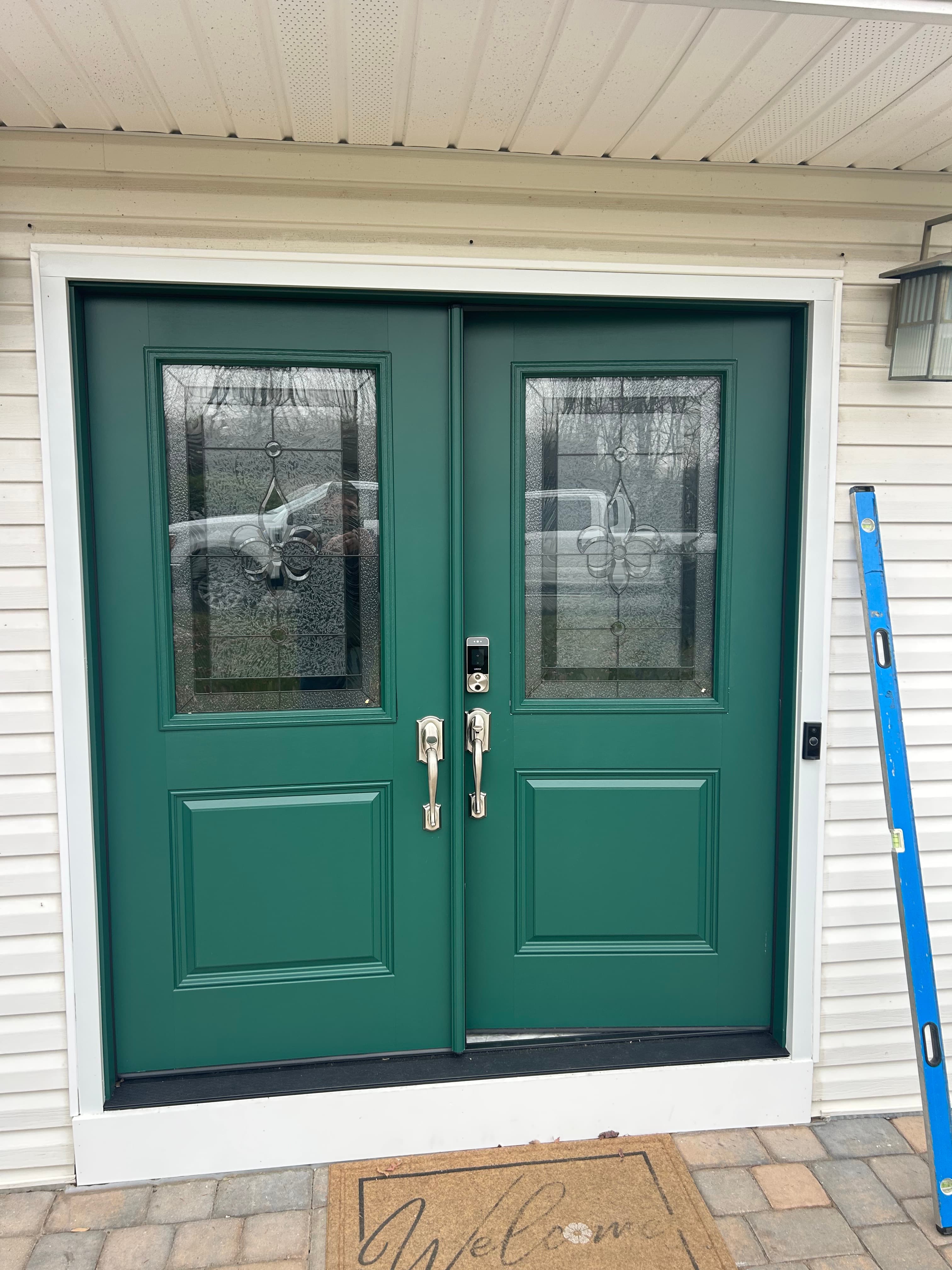Green dutch entry door with decorative leaded glass and welcome mat
