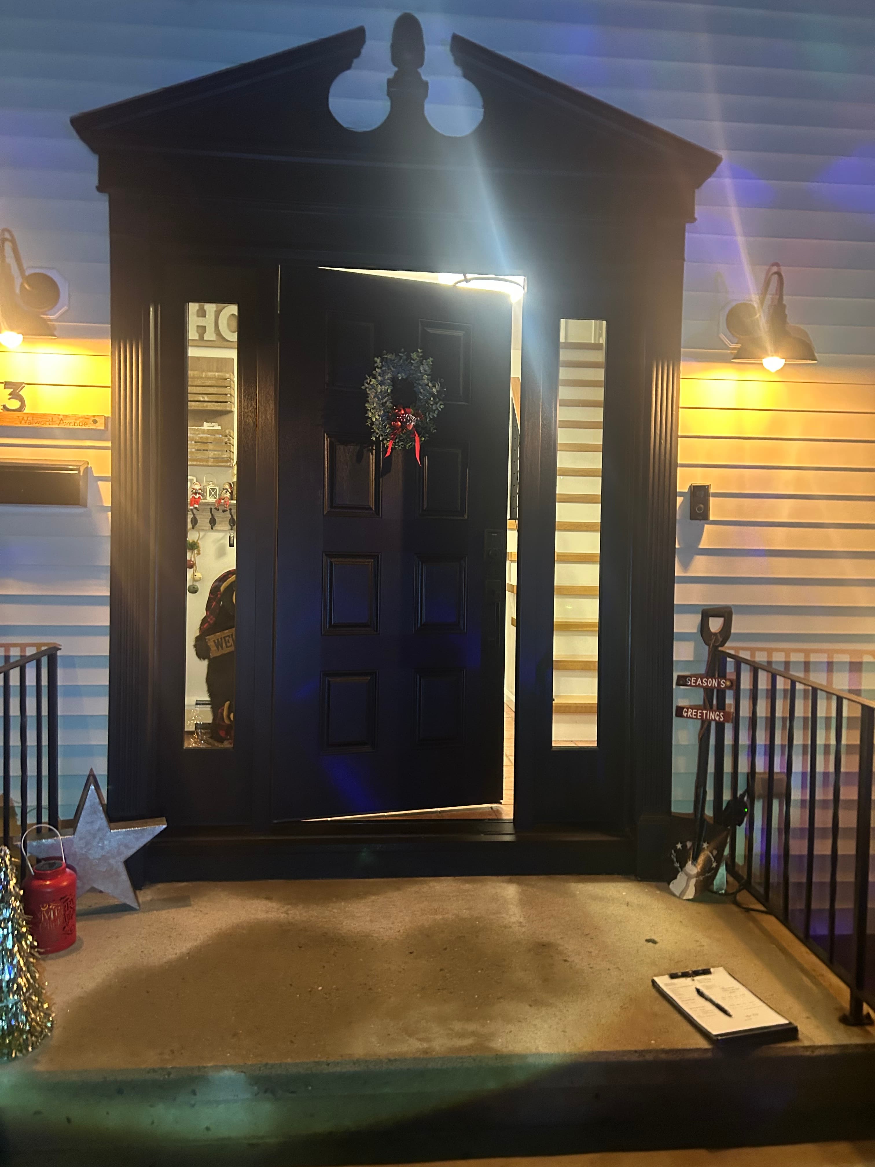 Black entry door with sidelights and transom on a covered porch