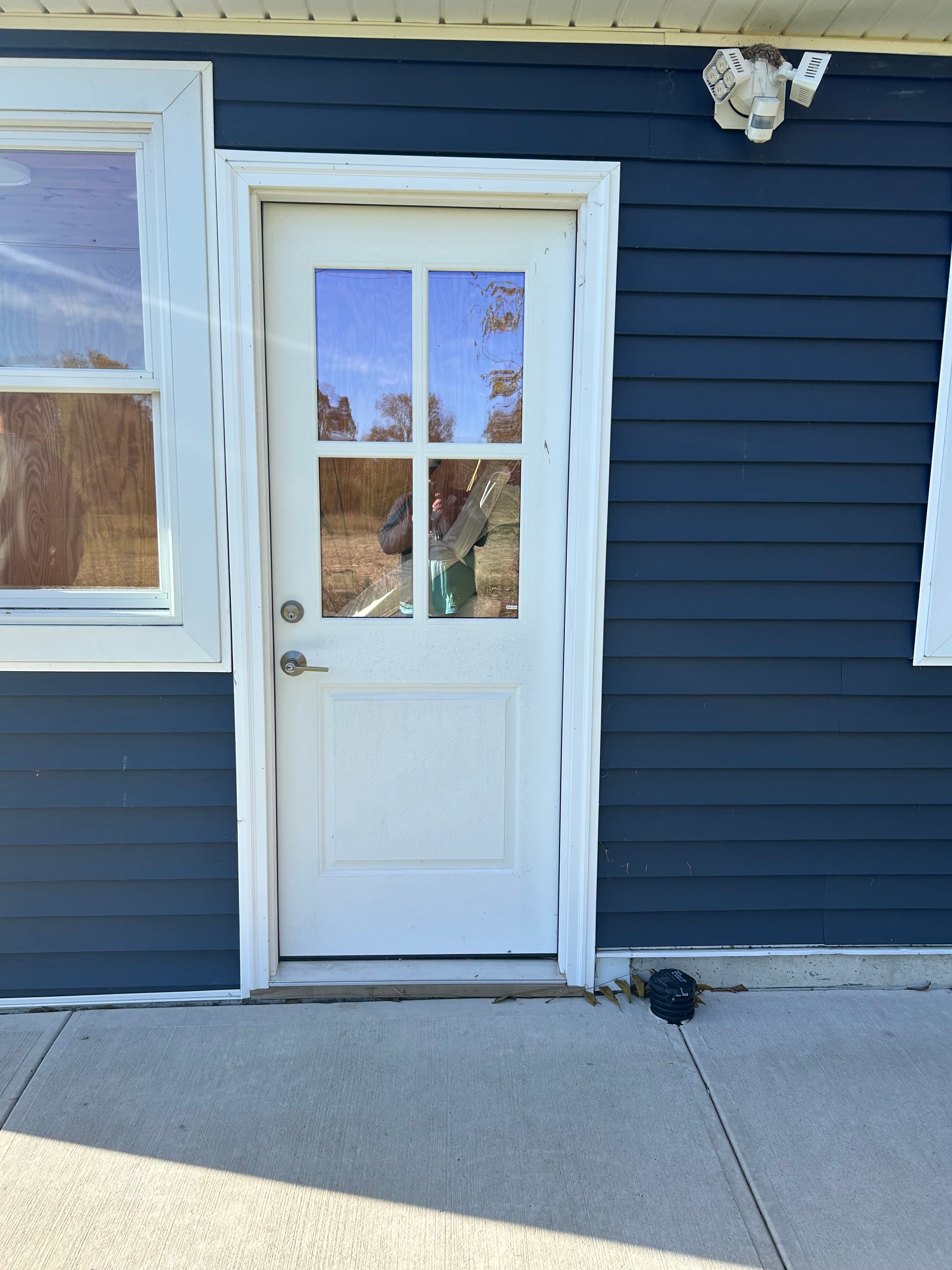 White entry door with four-lite glass and adjacent sidelight